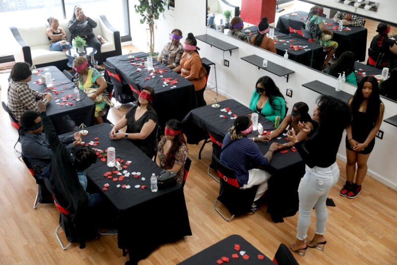 Blindfolded participants seated at decorated tables.