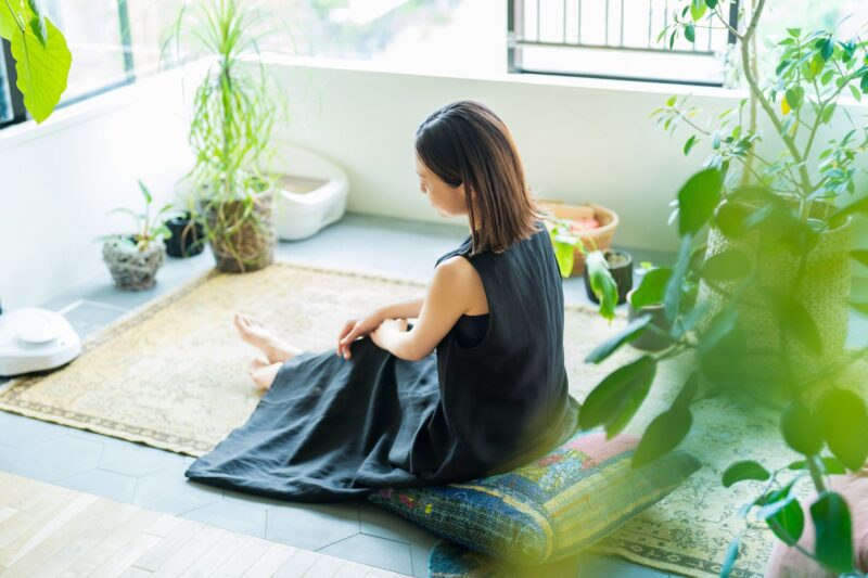 Woman in black dress seated on floor cushion